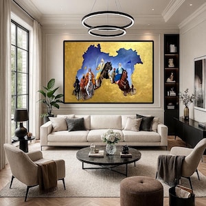 May include: A large framed painting depicting a historical scene with figures on horseback against a gold and blue background. The artwork hangs above a cream-colored sofa in a modern living room setting. The room features a round coffee table, two armchairs, and a patterned wooden floor.