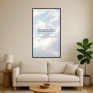 Può includere: Una stampa artistica incorniciata con un cielo con nuvole e testo in una sceneggiatura. La stampa è esposta sopra un divano beige in un soggiorno. Un tavolino e un tavolino in legno sono di fronte al divano.