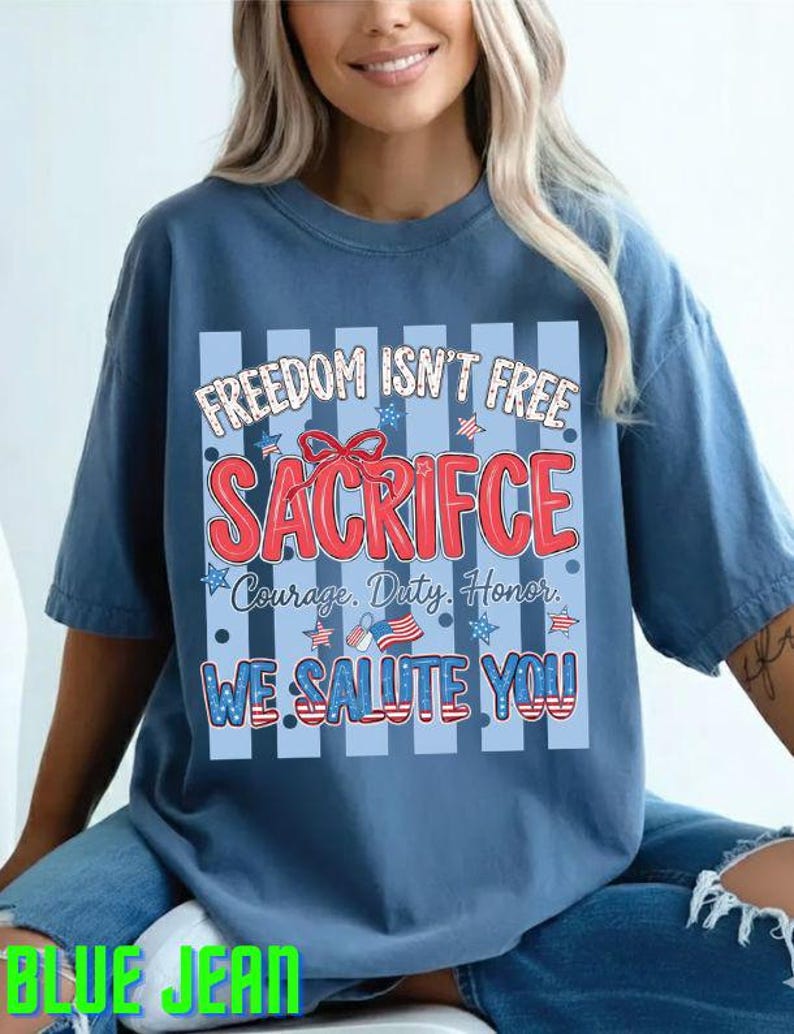 May include: A blue t-shirt with the text "FREEDOM ISN'T FREE SACRIFICE Courage. Duty. Honor. WE SALUTE YOU" in red, white, and blue. The shirt has a patriotic theme with stars and stripes.