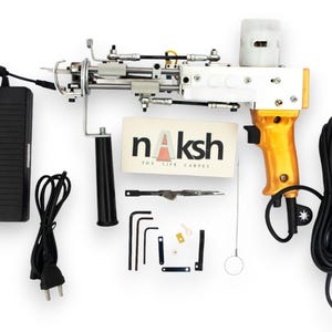 May include: A white and gold tufting gun with a black handle and power cord. The gun has a variety of small tools and accessories. The text "naksh THE LIFE CARPETS" is visible on a card.