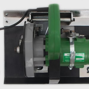 May include: A green and gray power tool with a black handle and cord. The tool is mounted on a black base with a silver metal frame. The tool has a label that reads "MC150".