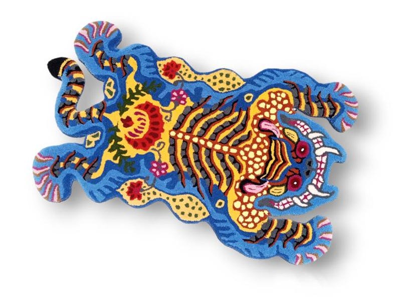 May include: A vibrantly colored rug in the shape of a tiger. The rug features a blue background with yellow, red, and black details. The tiger's body is adorned with intricate patterns and floral motifs, creating a decorative piece.