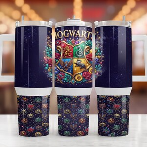 Könnte beinhalten: Ein zylindrischer Becher mit weißem Henkel und Deckel, der einen dunkelblauen Hintergrund mit einem Hogwarts-Wappen zeigt, umgeben von bunten Blumen und Edelsteinen. Der untere Teil zeigt ein wiederkehrendes Muster aus Wappen und Rosen.