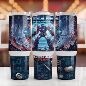 May include: A cylindrical tumbler with a white handle featuring a graphic of Optimus Prime, Autobot Commander, in a blue and red robotic form. The lower section displays technical schematics labeled Transformation System with blue line drawings.