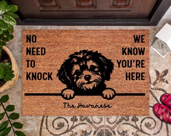 Può includere: Un zerbino rettangolare in fibra di cocco naturale. Il tappeto presenta una silhouette nera di un cane Havanese con il testo "NO NEED TO KNOCK WE KNOW YOU'RE HERE" e "The Havanese".