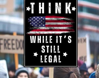 May include: A black sign with white text and an American flag design. The text reads "THINK" above the flag and "WHILE IT'S STILL LEGAL" below. The sign is surrounded by a crowd of people.