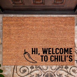 May include: A rectangular coir doormat with the text "HI, WELCOME TO CHILI'S" and a chili pepper graphic in black. The mat is brown and sits on a patterned tile floor.