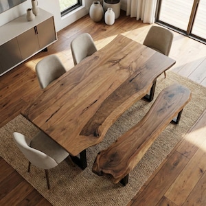 May include: A wooden dining table and bench set with live edges and black metal legs. Four beige upholstered chairs surround the table. The set sits on a woven rug, with a hardwood floor.