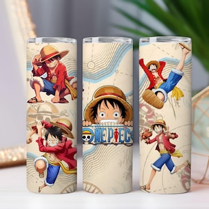Może przedstawiać: Trzy kubki ze stali nierdzewnej z ilustracjami postaci z serii anime One Piece. Postać jest przedstawiona w różnych pozach akcji, w czerwonej kurtce, niebieskich szortach i słomkowym kapeluszu. Tło ma wzór mapy.