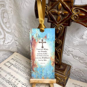 May include: A blue and brown bookmark with a cross and the text "I am the Way, the Truth, and the Life: no man cometh unto the Father but by Me. John 14:6" on a wooden easel.