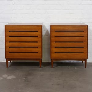 Par de cómodas altas de teca de estilo vintage de mediados de siglo con tiradores esculpidos.