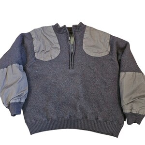 May include: A dark gray sweater with a half-zip closure and reinforced shoulders and elbows. The sweater has a ribbed knit collar, cuffs, and hem.