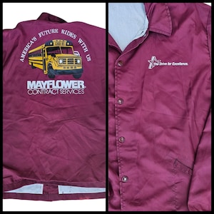 May include: Maroon Mayflower Contract Services jacket. The back features a yellow school bus graphic with the text "America's Future Rides With Us." The front has a star logo and the text "The Drive for Excellence."