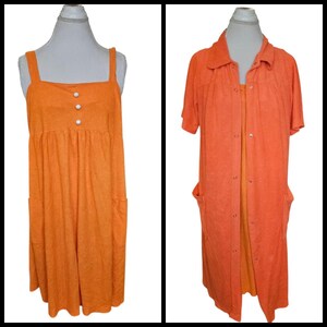 May include: Two orange dresses on mannequins. The first is a sleeveless sundress with a square neckline, three white buttons, and two pockets. The second is a short-sleeved robe with a collar, snap closures, and two pockets. Both are made of a textured fabric.