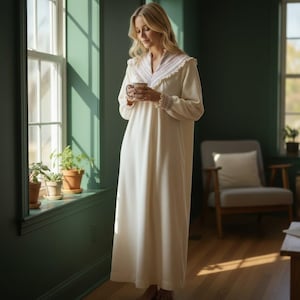 May include: A long, cream-colored nightgown with a V-neckline and long sleeves. The neckline and cuffs are trimmed with a delicate, patterned lace. The nightgown is worn by a person holding a mug.