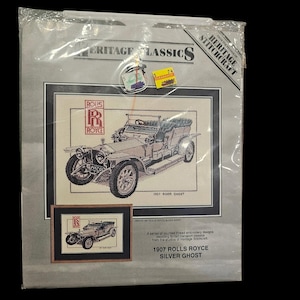 May include: A Heritage Classics counted thread embroidery kit featuring a 1907 Rolls Royce Silver Ghost. The packaging displays the car illustration, the Rolls Royce logo, and text including 1907 ROLLS ROYCE SILVER GHOST. It is sealed in plastic.