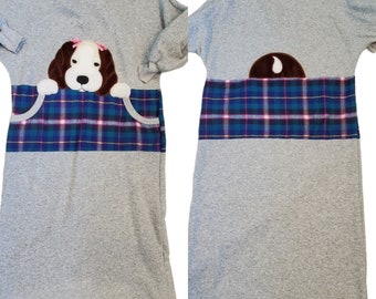May include: A gray long-sleeved dress with a plaid panel and a brown felt dog applique. The dog has pink bows on its ears.