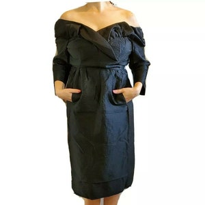 May include: A black off-the-shoulder dress with a ruched neckline and long sleeves. The dress has a fitted bodice and a flowing skirt.