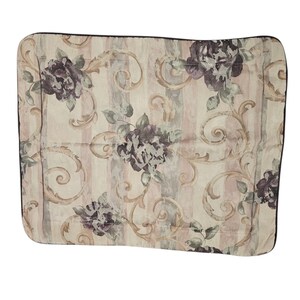 May include: Rectangular pillow with a floral pattern. The pillow features a cream-colored background with vertical stripes in shades of beige and gray. Large, dark purple floral designs are scattered across the surface, with green leaves and gold-colored swirls.