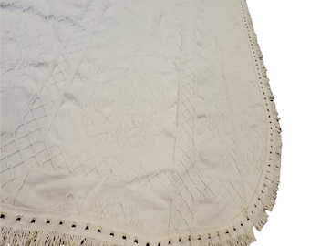 May include: A white round rug with a textured diamond pattern and a fringe border.