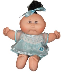 May include: A Cabbage Patch Kids doll with a bald head, brown eyes, and rosy cheeks. The doll wears a light blue dress with lace trim and a matching bow in its black hair. A blue flower is on the dress.