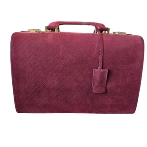 May include: A burgundy quilted leather travel case with gold hardware and a small leather tag.
