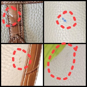 May include: Close-up of a leather handbag with a textured surface. The bag features a brown crocodile-embossed leather strap and a cream-colored body. The image shows minor imperfections, including a blue stain and small marks.
