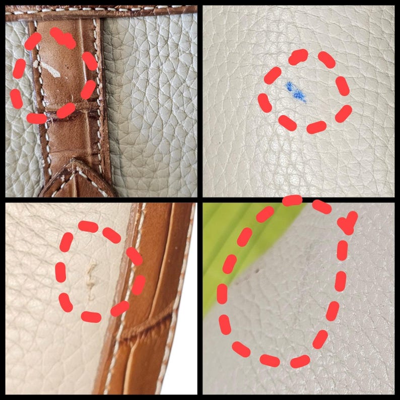May include: Close-up of a leather handbag with a textured surface. The bag features a brown crocodile-embossed leather strap and a cream-colored body. The image shows minor imperfections, including a blue stain and small marks.