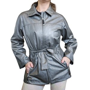 May include: A silver metallic jacket with a zipper closure, a belt, and two pockets. The jacket has a stand-up collar.