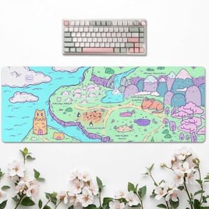 Puede incluir: Una alfombrilla de escritorio rectangular con un mapa ilustrado a todo color que muestra agua azul claro, tierra verde, monta&ntilde;as moradas y &aacute;rboles rosas. El mapa incluye etiquetas de texto como Mallow Marsh, Fudgling Patch y Boba Bubble Springs.