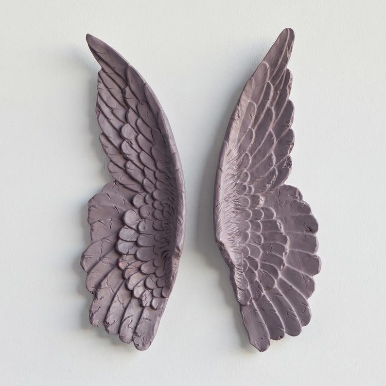 Peut inclure: Deux ailes d'ange murales assorties, de couleur mauve. Les ailes pr&eacute;sentent des motifs de plumes textur&eacute;s et d&eacute;taill&eacute;s, sur un fond blanc uni. Les ailes sont un objet d&eacute;coratif.