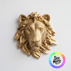 Puede incluir: Escultura de pared con cabeza de león dorada con detalles en la melena y rasgos faciales. La escultura está montada en una pared blanca. La imagen incluye una rueda de color con el texto "See more".