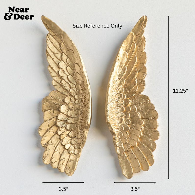 Peut inclure: Deux ailes d'ange dor&eacute;es pour la d&eacute;coration murale. Chaque aile mesure 8,9 cm de large et 28,6 cm de haut. Les ailes sont faites d'un mat&eacute;riau textur&eacute; et sont affich&eacute;es sur un fond blanc. Le texte "Near & Deer" est dans le coin sup&eacute;rieur gauche.