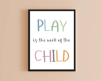 May include: A framed print with the words "PLAY is the work of the CHILD" in colorful letters. The word "PLAY" is in blue and green, the word "CHILD" is in pink and orange, and the rest of the text is in black.
