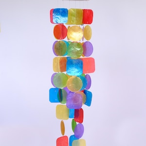 May include: A colorful wind chime with a wooden top and a cascade of iridescent, square, and circular shell pieces in shades of blue, green, yellow, orange, and purple. The chime is suspended by thin strings.