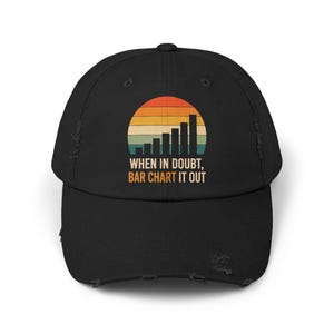 May include: A black distressed baseball cap featuring a graphic of a bar chart set against a semi-circular sunset in shades of orange, yellow, and teal. Below the graphic, the text reads: WHEN IN DOUBT, BAR CHART IT OUT in white and orange.