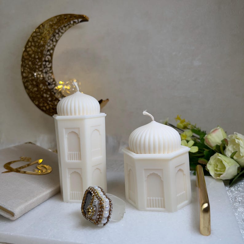 Stilvolles islamisches Kerzen Set für Ramadan mit zwei cremefarbenen Moschee-Kerzen im orientalischen Design. Sechseckige Formen, geriffelte Kuppeln und dekorative Fensterdetails. Kombiniert mit Halbmond-Deko, Blumen und Gebetszubehör – perfekt als Eid Geschenk oder muslimische Wohndeko.