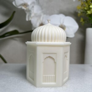 einer Moschee Kerze aus pflanzlichem Rapswachs.Die handgefertigte Skulpturkerze zeigt eine kuppelförmige Struktur,dezente architektonische Details.Perfekt als Ramadan islamische Dekoration,als liebevolles Geschenk zu Eid.harmoniert mit verschiedenen Einrichtungsstilen.Seitliche Ansicht einer hohen islamischen Moschee Kerze mit klaren Linien und minimalistischer Form.duftfrei und ungefärbt.Geeignet als moderne Ramadan Dekoration, islamische Deko für das Wohnzimmer, als hochwertiges zu Eid Mubarak