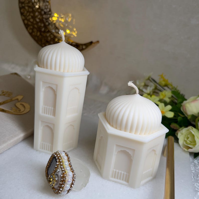 Ramadan Deko Kerzen im Moschee-Stil aus hochwertigem Wachs, mit feinen Fensterornamenten und Kuppelaufsatz. Arrangiert mit goldener Halbmond-Dekoration, Blumen und islamischem Zubehör. Ideal für festliche Ramadan Tischdeko, Gebetsraum oder als stilvolle Geschenkidee.Ideal als Ramadan Deko, Eid Geschenk oder stilvolle Tischdekoration. Die natürliche Farbe sorgt für eine ruhige, harmonische Wirkung im Raum.