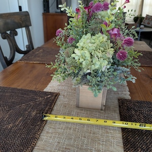 Pu&ograve; includere: Una tazza di ceramica bianca con manico nero e la scritta "But First, Coffee" in grassetto nero. La tazza &egrave; posta su uno sfondo sfocato, suggerendo un'atmosfera accogliente.