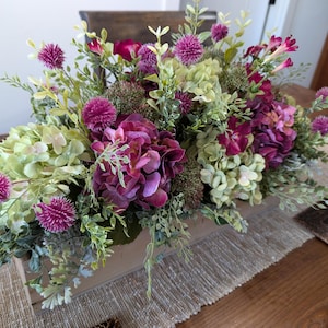 Pu&ograve; includere: Una tazza di ceramica bianca con manico nero e la scritta "But First, Coffee" in grassetto nero. La tazza &egrave; posta su uno sfondo sfocato, che suggerisce un'atmosfera accogliente.