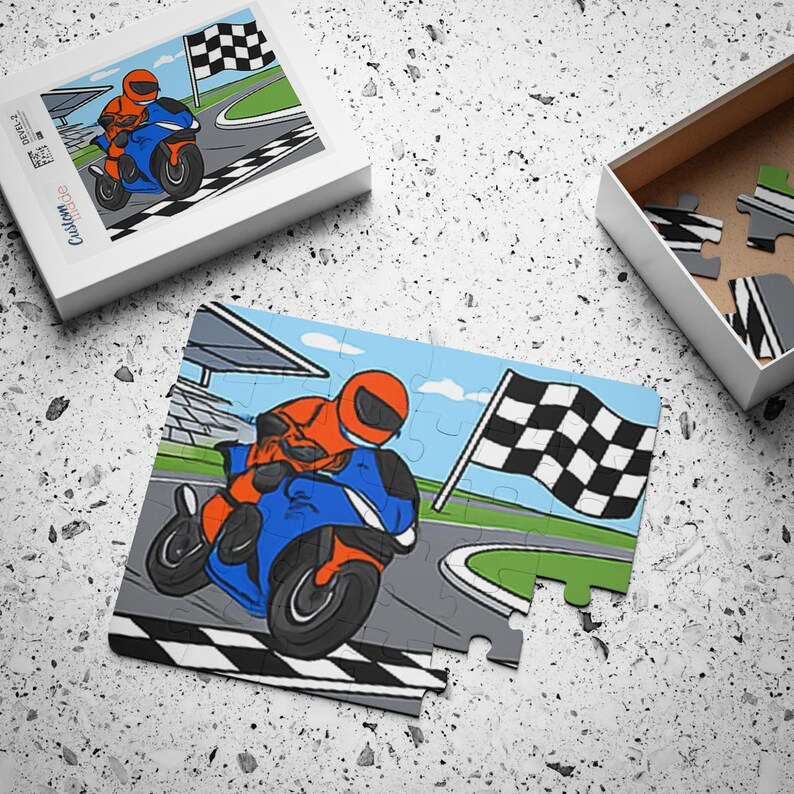 A completed motorbike puzzle lies on a textured gray surface next to its open box and lid showing the same illustration.