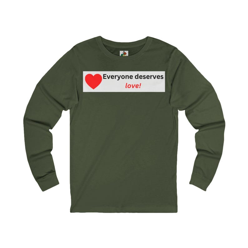Front view of an olive green long-sleeve t-shirt with a white rectangular chest graphic containing a red heart and the text Everyone deserves love!.