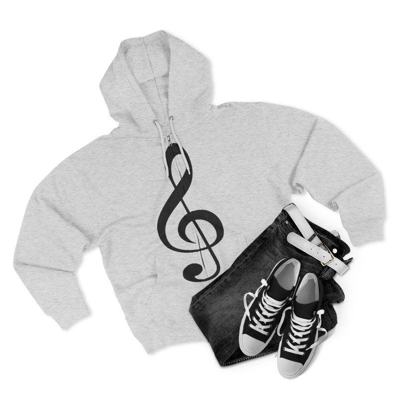 A grey zip-up hoodie with a treble clef next to black and white canvas sneakers and dark jeans.