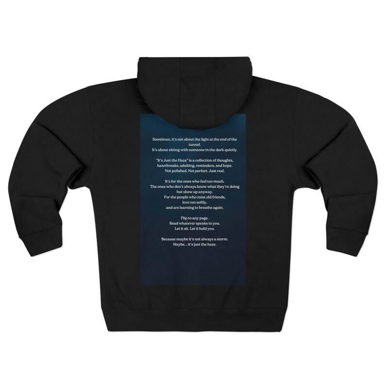 Black hooded zip-up sweatshirt. The back displays a dark blue rectangle with white text, including the phrase "It's Just the Haze" and other lines of poetry. The hoodie has a hood and a full-length zipper.