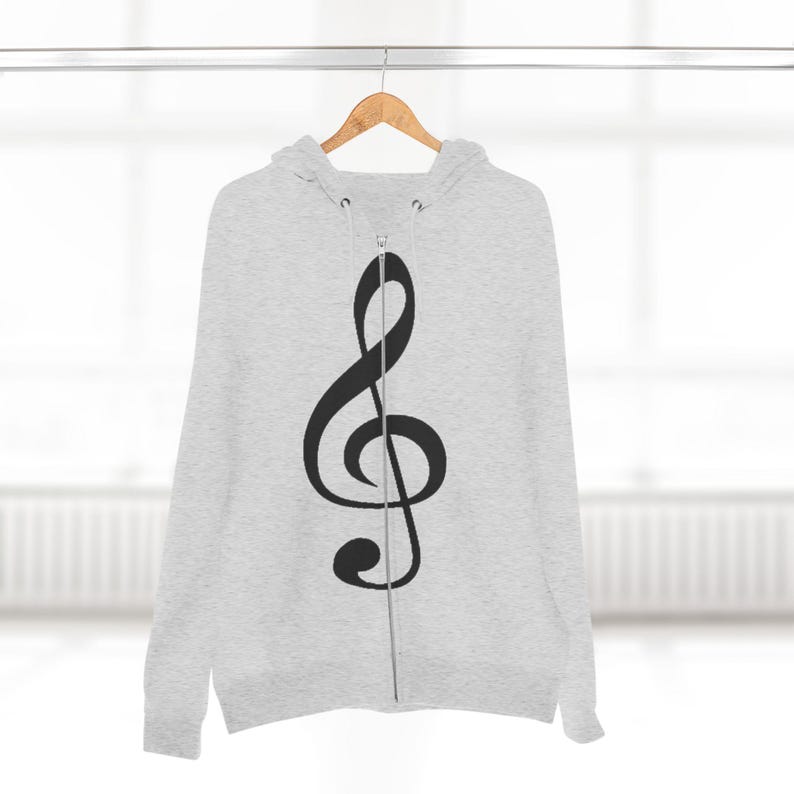 A grey zip-up hoodie with a black treble clef hanging from a wooden hanger against a neutral background.