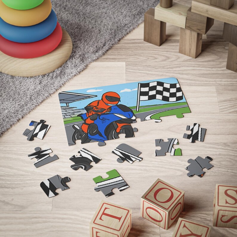 A partially assembled motorbike puzzle on a wooden floor, surrounded by loose puzzle pieces, wooden alphabet blocks, and a stacking ring toy.