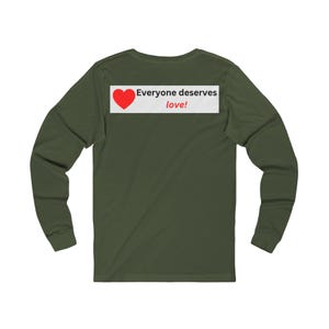 Back view of an olive green long-sleeve t-shirt with a white rectangular graphic on the upper back showing a red heart and the text Everyone deserves love!.