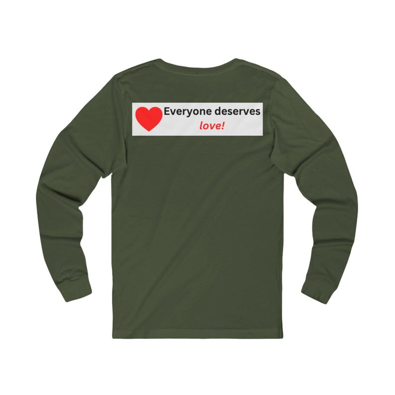 Back view of an olive green long-sleeve t-shirt with a white rectangular graphic on the upper back showing a red heart and the text Everyone deserves love!.