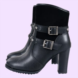 May include: Black leather ankle boots with a block heel. The boots feature two buckled straps with silver-tone hardware and decorative studs. The upper portion of the boot is made of black suede.